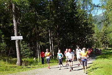 A group of people are running in the woods near a restaurant sign