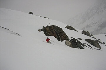 A man in a red jacket skiing down a snowy mountain