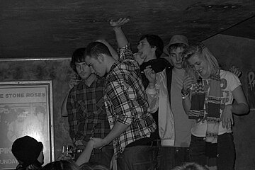 A group of people standing in front of a sign that says the stone roses