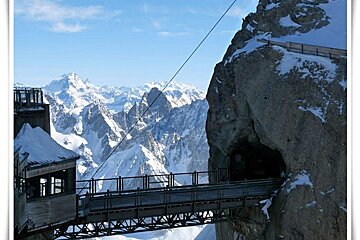 A bridge over a cliff with mountains in the background