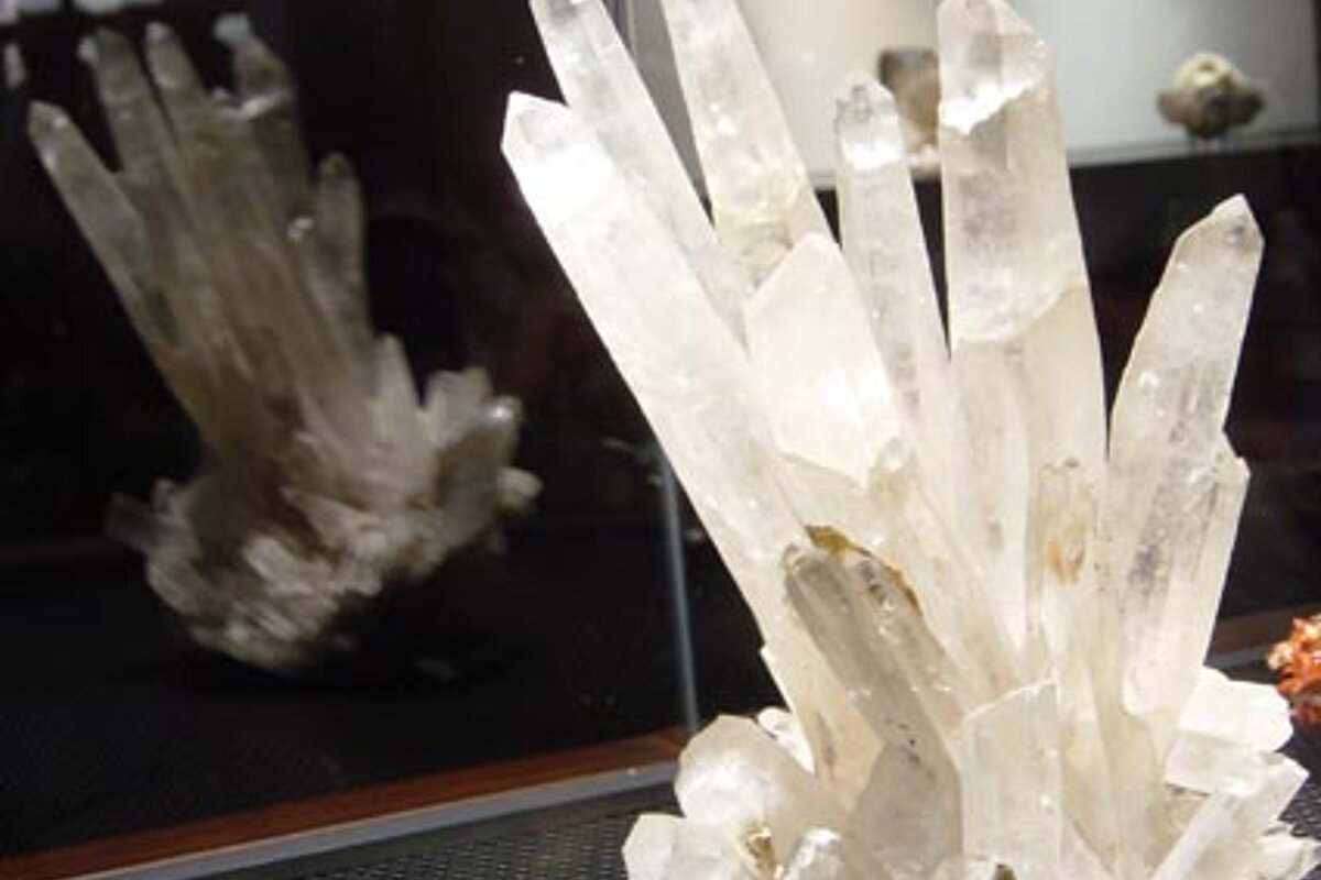 A large crystal cluster is sitting on a table in front of a mirror