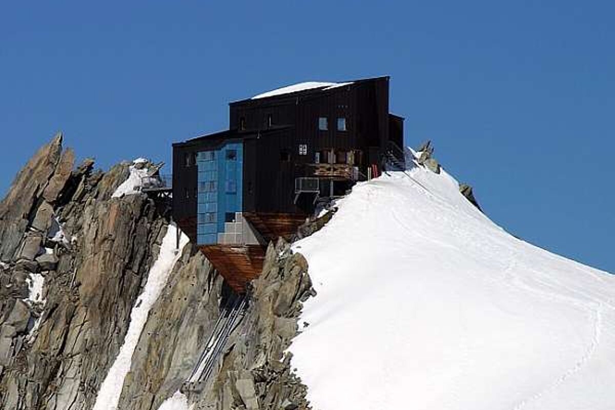A large building is sitting on top of a snow covered mountain