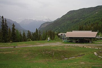 A building in the middle of a field with mountains in the background