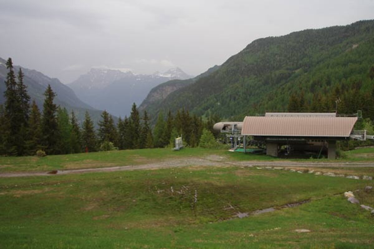 A building in the middle of a field with mountains in the background