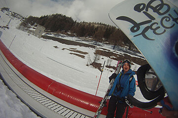 A person holding skis and a snowboard that says ' bec ' on it