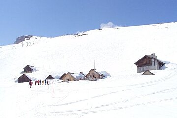 A group of people are walking down a snowy hill