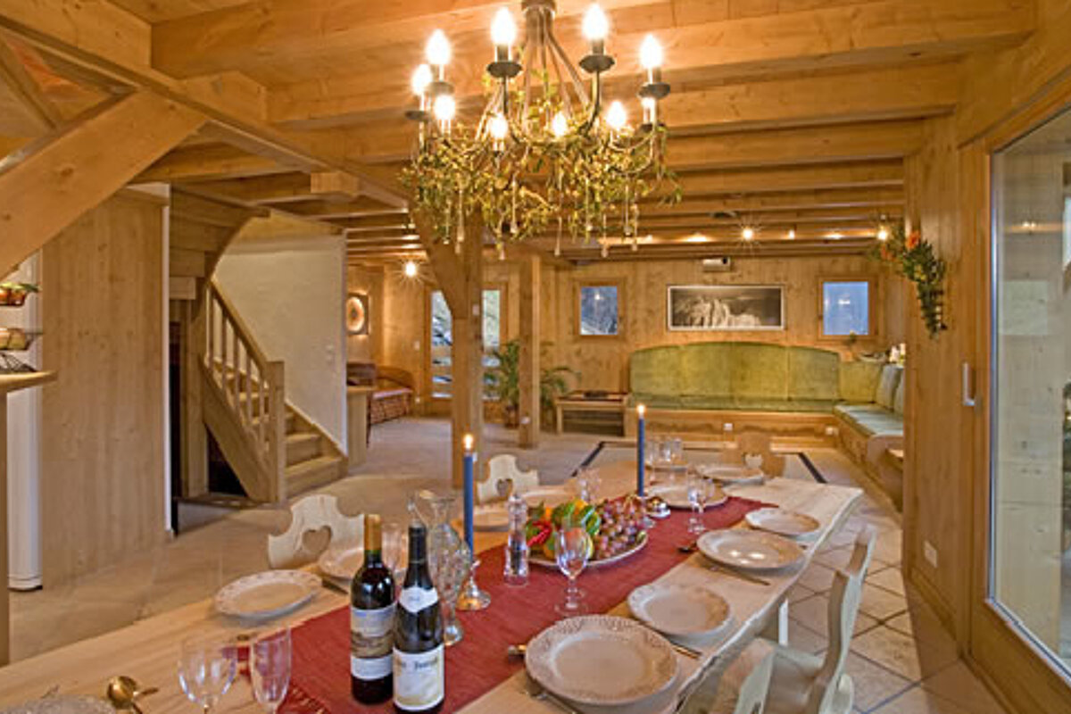 A bottle of wine sits on a table with plates and glasses