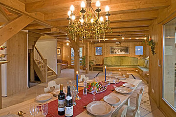 A bottle of wine sits on a table with plates and glasses