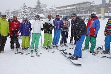 Group of skiers and boarders posing for photo in snow
