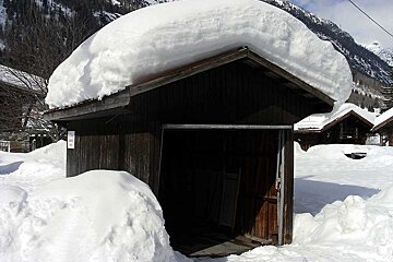 A snow covered shed with a sign that says ' a ' on it
