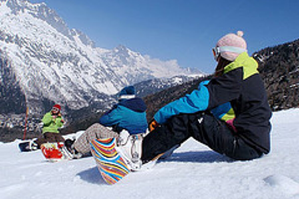 A group of snowboarders sitting on top of a snow covered mountain