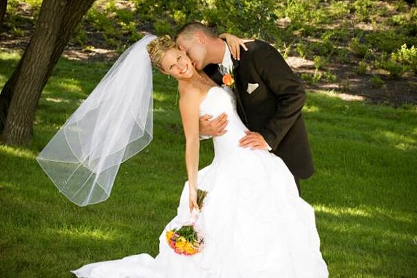 a picture of a groom kissing his bride on a lawn