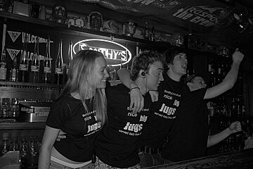 A group of people wearing black shirts that say jugs