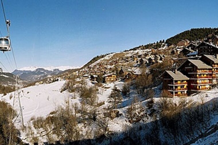 A ski lift is going down a snowy mountain
