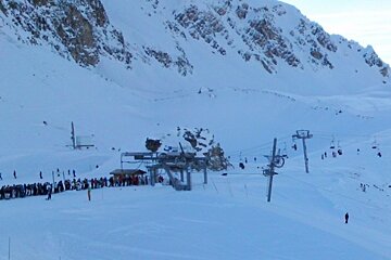 A group of people are waiting for a ski lift on a snowy mountain