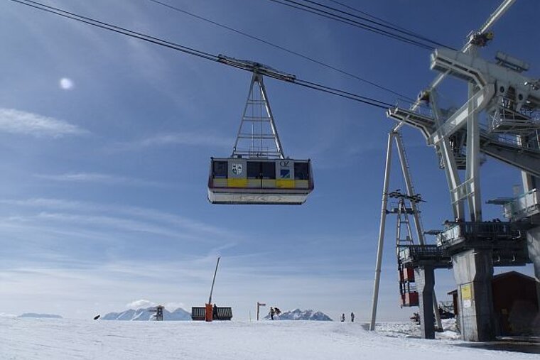 A ski lift is going up a snowy mountain