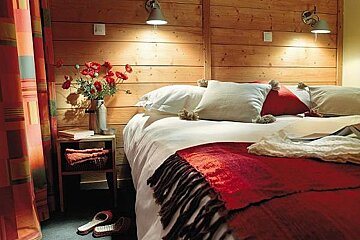 There is a bed with a red blanket and pillows in the bedroom