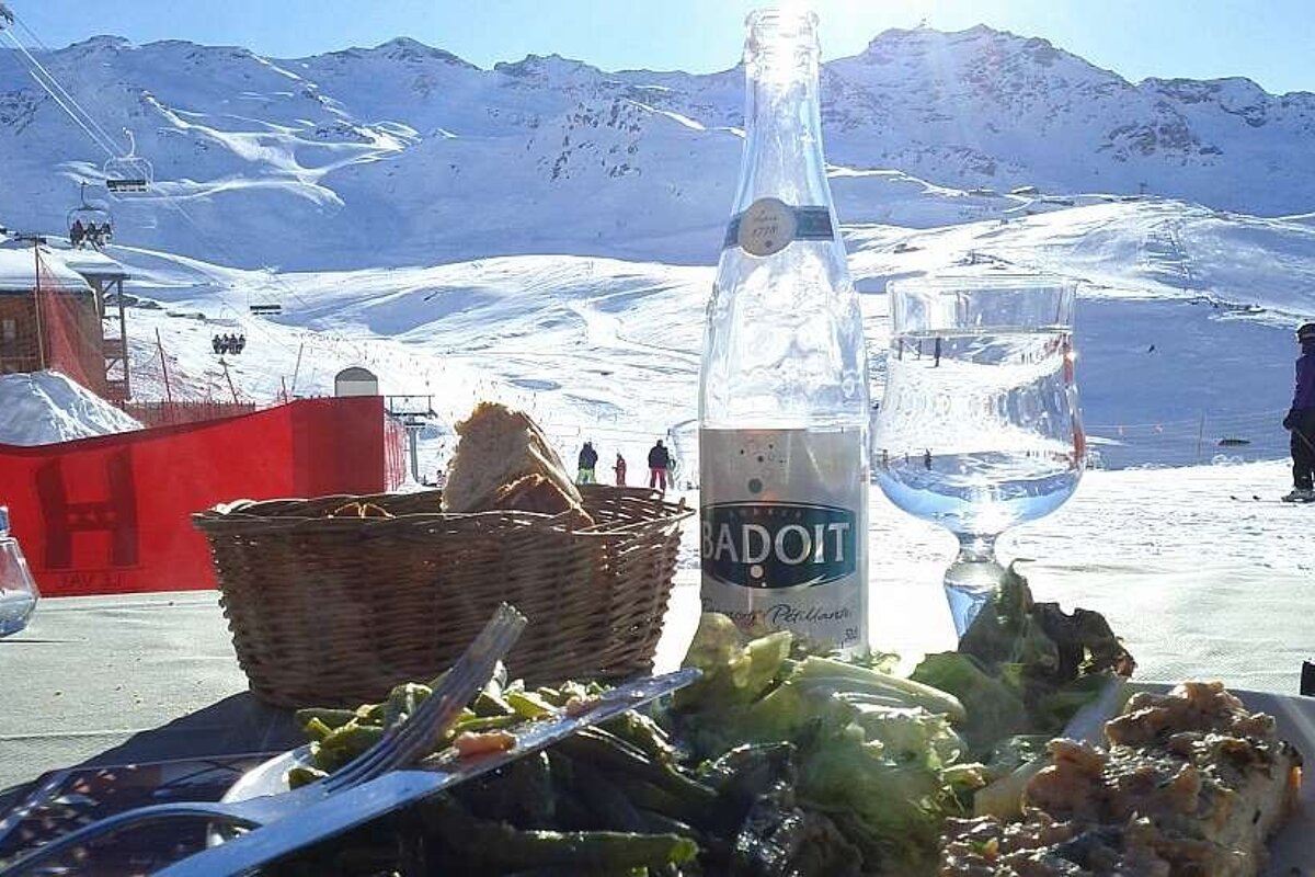 A bottle of badoit water sits next to a basket of bread
