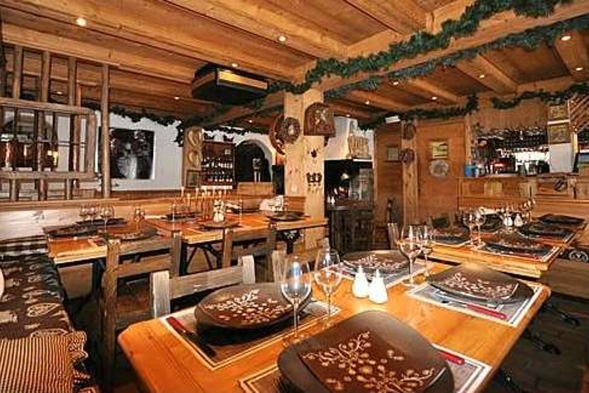 A restaurant with wooden tables and chairs and plates on them