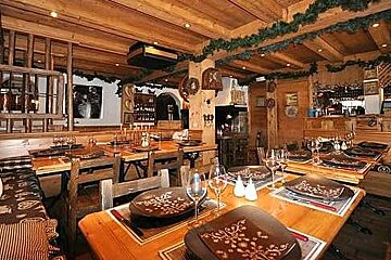 A restaurant with wooden tables and chairs and plates on them