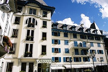 A large white building with blue shutters and flowers on the balconies