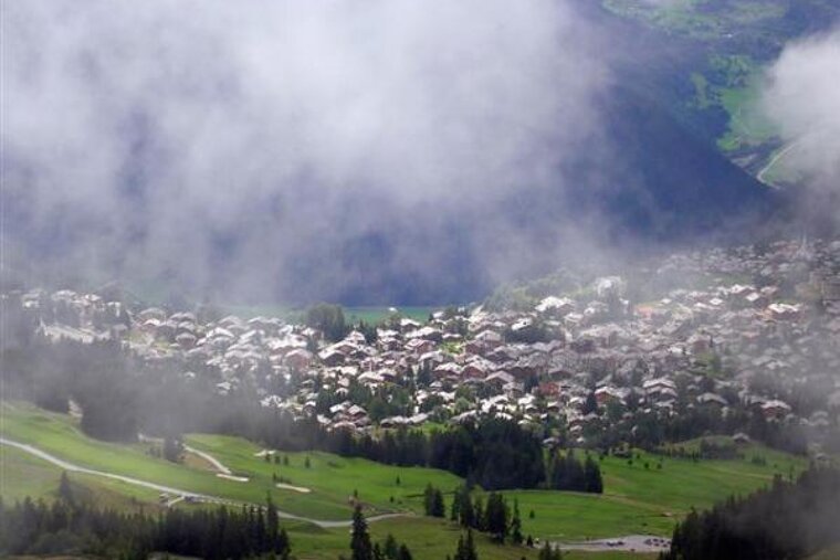 An aerial view of a small town in the mountains covered in fog
