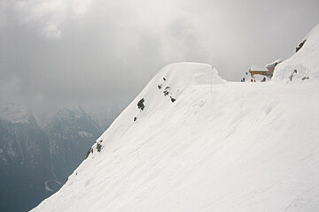A snowy mountain with a building in the background