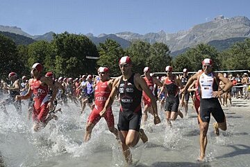 A group of athletes are running in the water and one of the sponsors is toyota