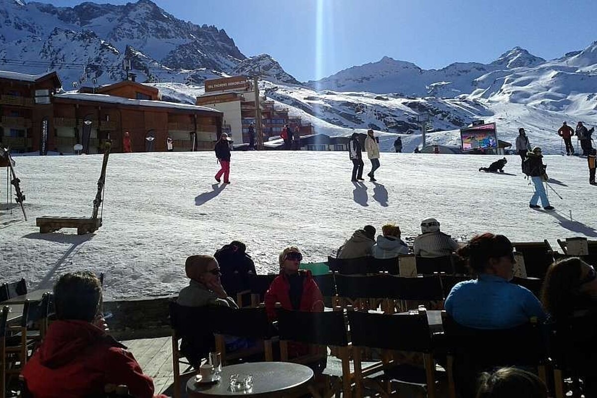 A group of people sit at tables in front of a ski resort