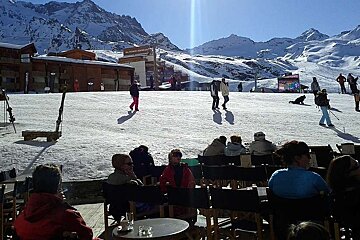 A group of people sit at tables in front of a ski resort
