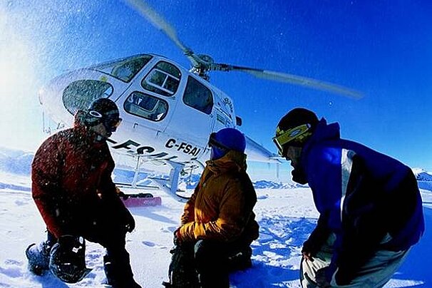 an image of 3 people near a helicopter in the snow