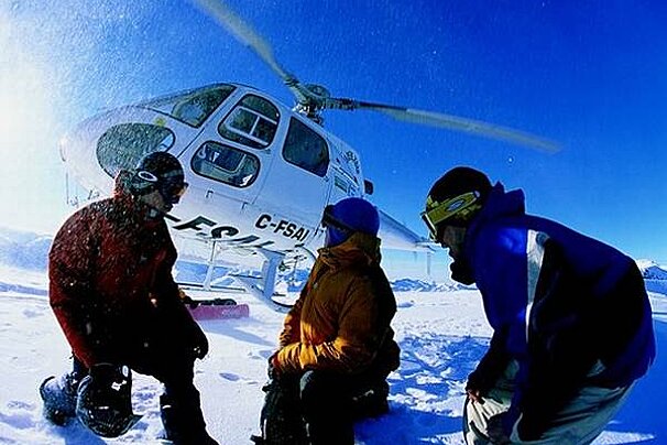 an image of 3 people near a helicopter in the snow