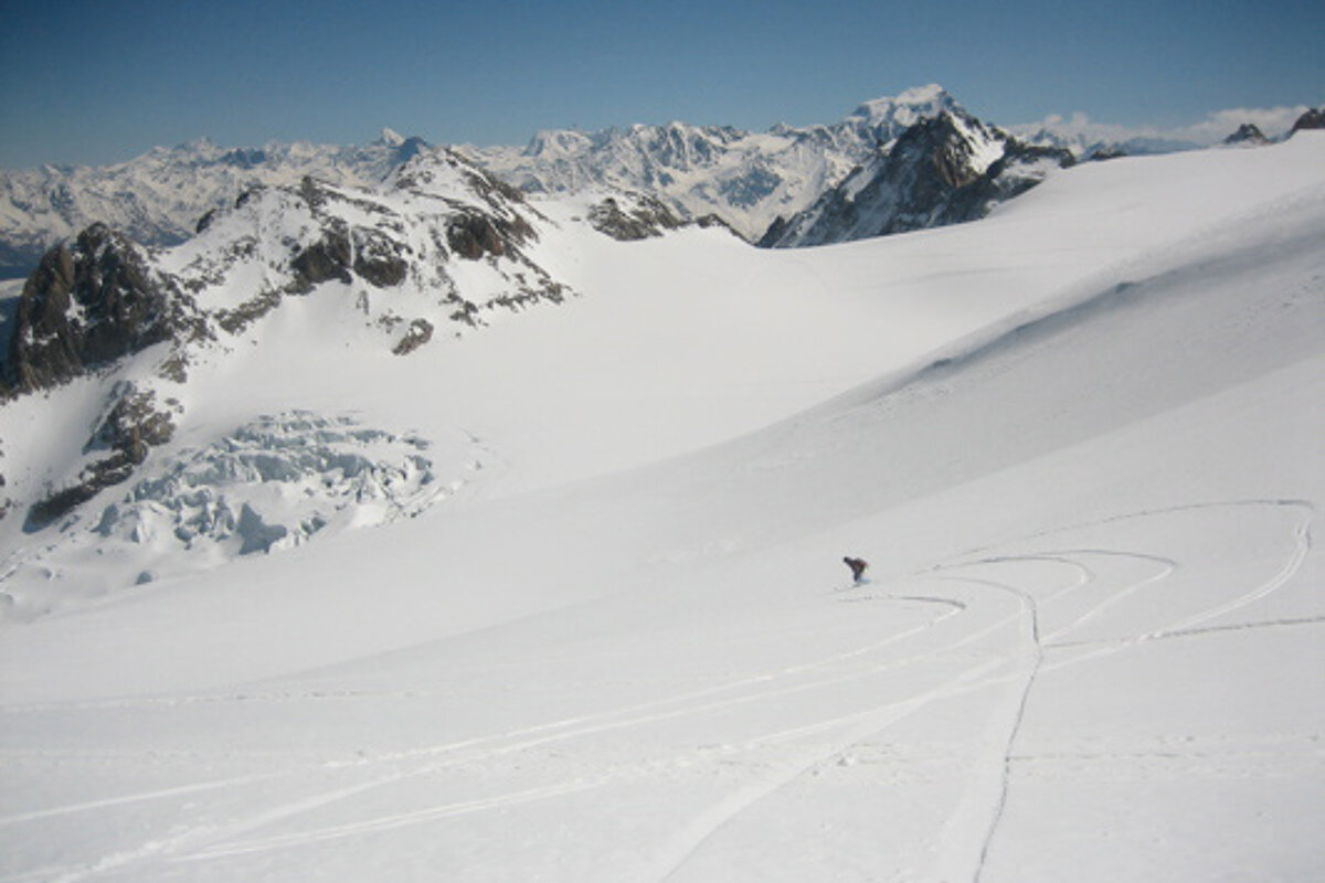 A person skiing down a snowy slope with mountains in the background