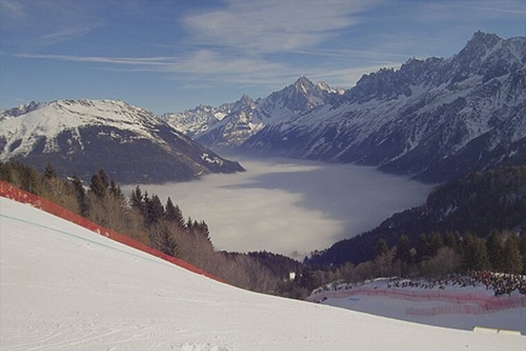 A ski slope with a red fence and mountains in the background