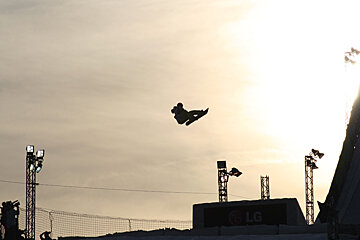A snowboarder flies through the air in front of an lg sign