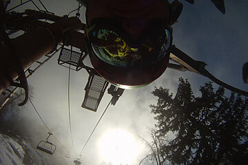 A person wearing goggles is riding a ski lift
