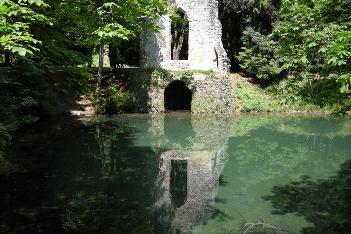 A stone archway is reflected in a body of water