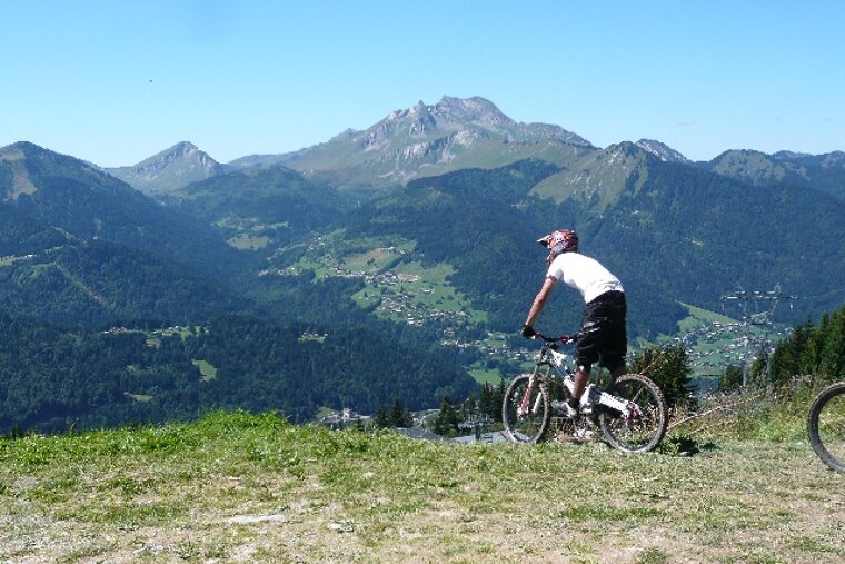 A person riding a bike on top of a hill with mountains in the background