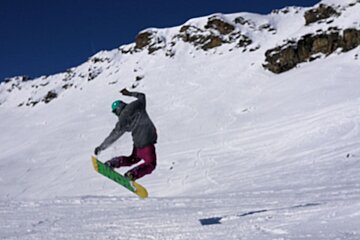 An image of a snowboarder getting some air off-piste