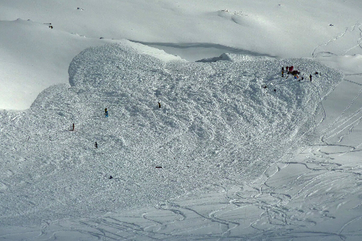 A large pile of snow with skiers on top of it
