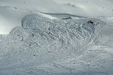 A large pile of snow with skiers on top of it
