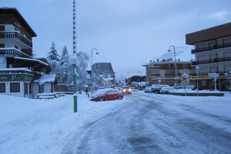A snowy street with a building that says nes on it