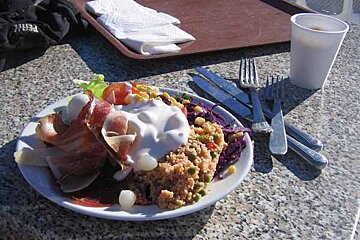 A plate of food sits on a granite table next to a tray and a cup