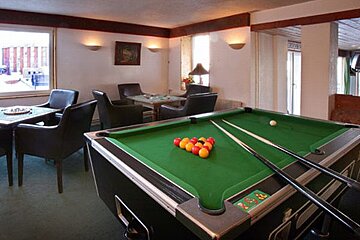 A pool table in a room with chairs and tables