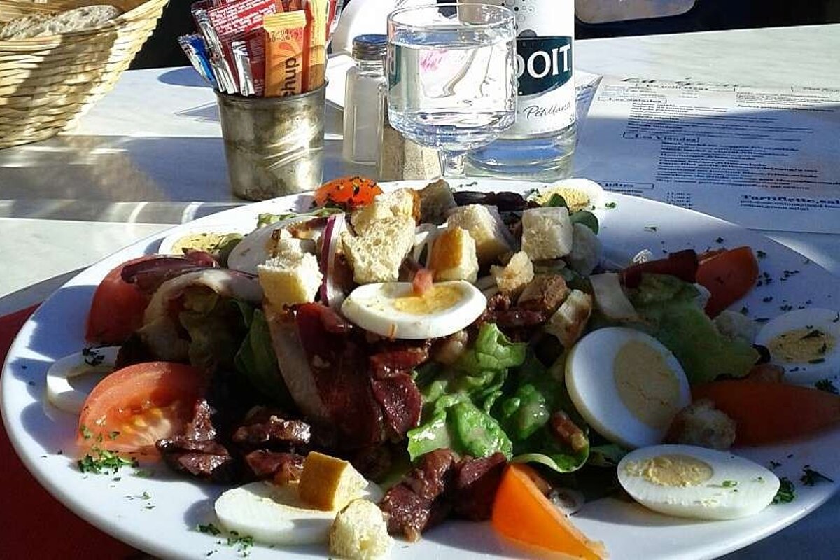 A salad on a plate next to a bottle of doit water