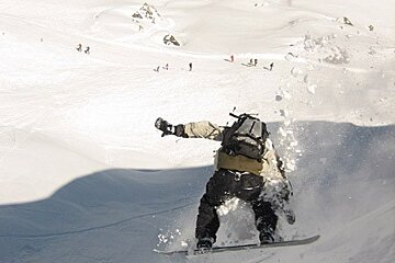 A snowboarder is going down a snow covered slope