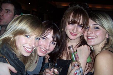 A group of women are posing for a picture and one of them is holding a bottle of bacardi