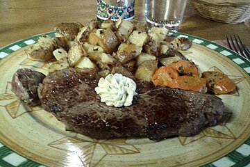 an image of a steak and potatoes on a plate with a dollop of butter on top