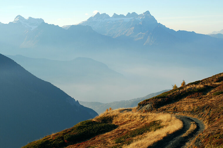 A dirt road in the mountains with mountains in the background