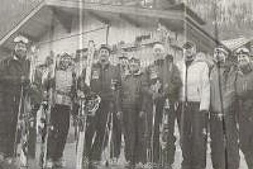 A group of people standing in front of a building holding skis